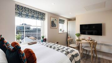 Una habitación de hotel moderna con una cama grande, un comedor y un televisor.