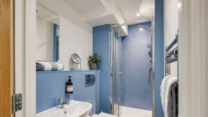 Un baño moderno con lavamanos, inodoro y ducha con mampara de vidrio.