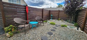 A patio with two wicker chairs, a small round table, and a red paddle.