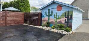 A building with a painted exterior featuring a desert landscape, a wooden gate, and a paved driveway.