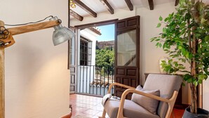 A room with a wooden rocking chair, a potted plant, and a view of a courtyard through an open door. - Genteel Home Mirador de los Reyes (Granada)