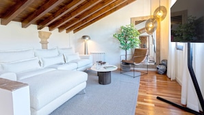 A modern living room with a high ceiling, wooden beams, a white sofa, a round coffee table, and a potted plant. - Genteel Home Mirador de los Reyes (Granada)