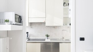 Una cocina moderna con armarios blancos, lavavajillas de acero inoxidable, microondas y un fregadero.