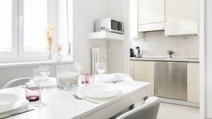 Una cocina moderna con armarios blancos, un microondas integrado y un lavavajillas.