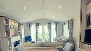 Een moderne woonkamer met een bank, televisie en een open haard.