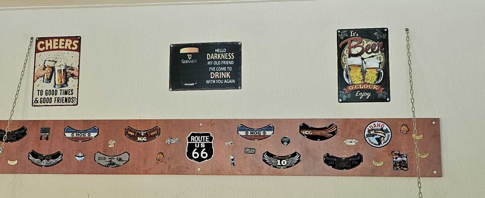 Una pared con varios carteles y recuerdos, incluyendo un cartel de 'Cheers', un cartel de 'Hello Darkness' y un cartel de 'Beer'.