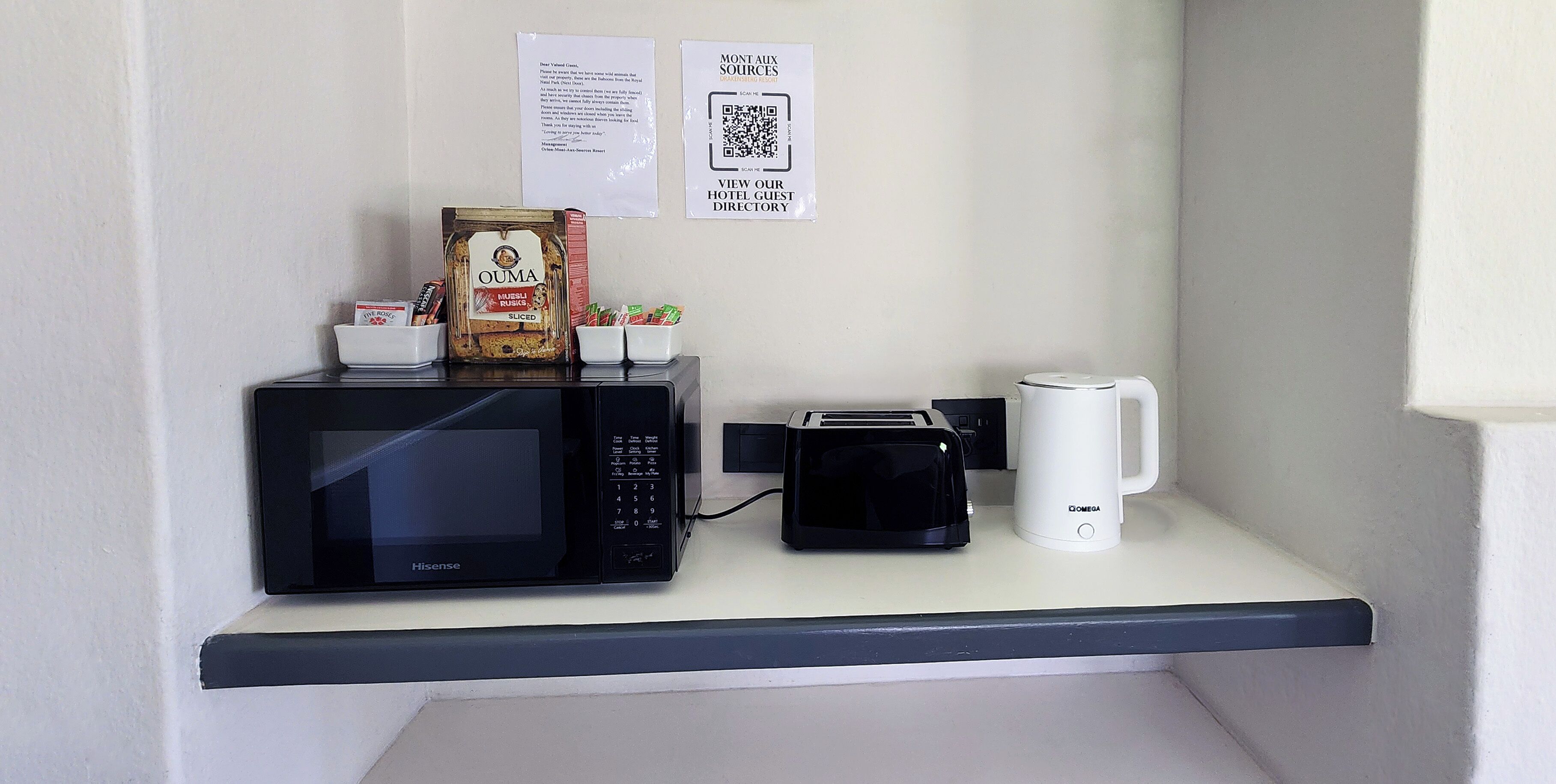 A kitchenette with a microwave, toaster, coffee maker, and a bag of sliced bread.