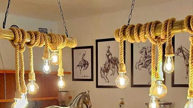 Un espace bar avec des tabourets en bois, une sculpture de cheval et un luminaire en forme de corde.
