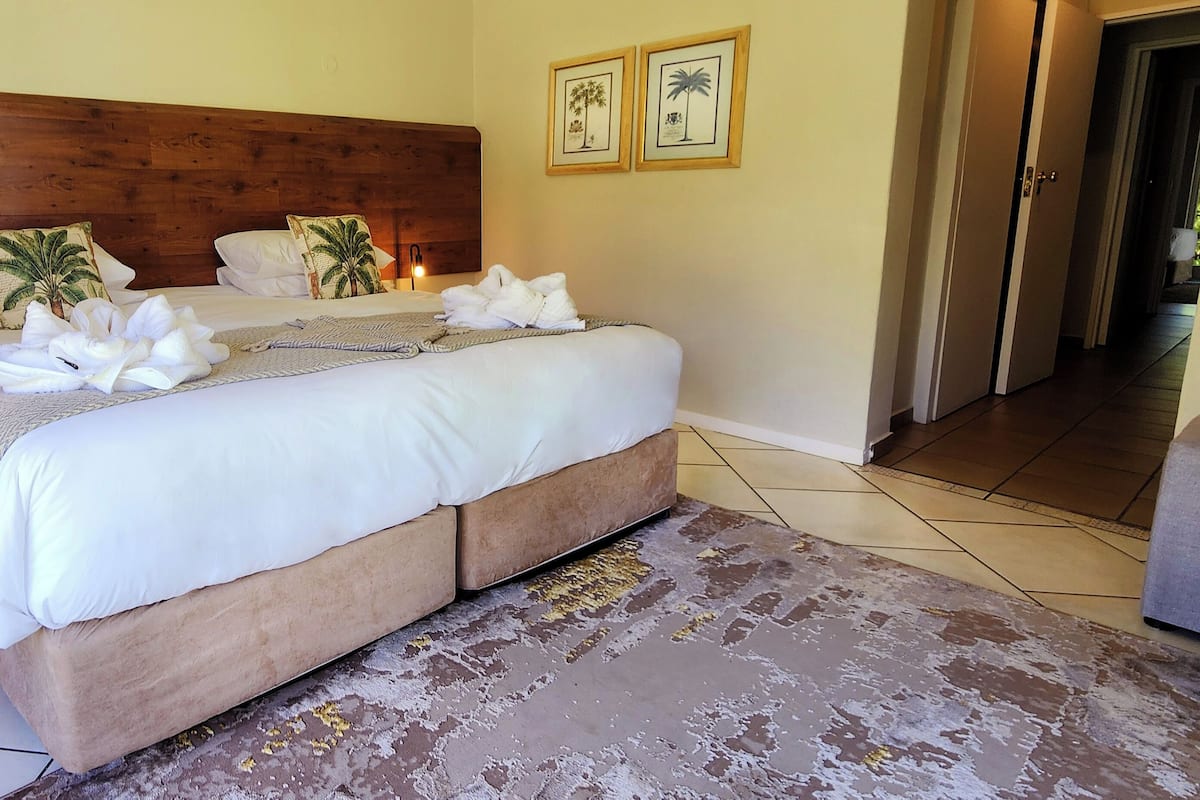 A neatly made bed with white linens, a wooden headboard, and two framed pictures on the wall.