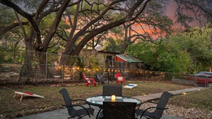 A patio with a round table and four chairs, surrounded by a fence and trees. - The Yellow Rose of SoCo:Charming Home Steps from South Congress and 1 mile to Downtown (Austin)