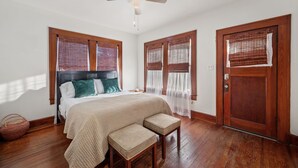 A bedroom with a bed, two bedside tables, a ceiling fan, and a wooden door. - The Yellow Rose of SoCo:Charming Home Steps from South Congress and 1 mile to Downtown (Austin)