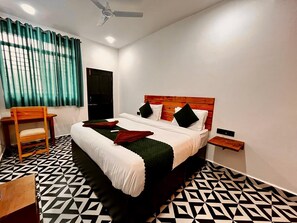 A neatly arranged bedroom with a bed, a chair, a small table, and a wooden headboard. - Bob Beach Hotel (Calangute)