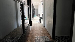 Un couloir avec des carreaux de sol à motifs, une porte sur la droite et une fenêtre sur la gauche.
