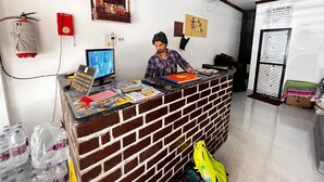 Un comptoir d’accueil avec un ordinateur, un détecteur d’incendie rouge et un panneau « Il est interdit de fumer ».