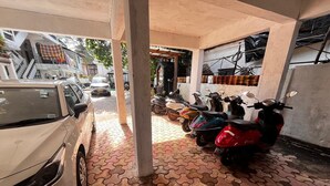 Un espace de stationnement couvert où sont garées une voiture blanche et plusieurs scooters.