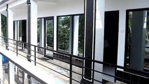 Un bâtiment doté de grandes fenêtres, d’un balcon avec une rambarde en métal et d’une façade blanche.