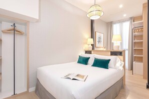 A neatly arranged hotel room with a large bed, bedside lamps, a wardrobe, and a mirror. - Genteel Home Museo (Seville)