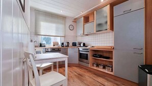 Une cuisine compacte comprenant une table à manger, des placards et une horloge murale.
