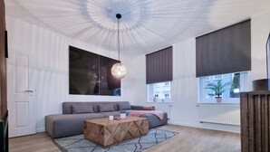 A modern living room with a sofa, a coffee table, and a hanging light fixture.