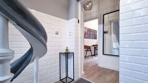 A staircase with a white wall and a door leading to a room with a window.