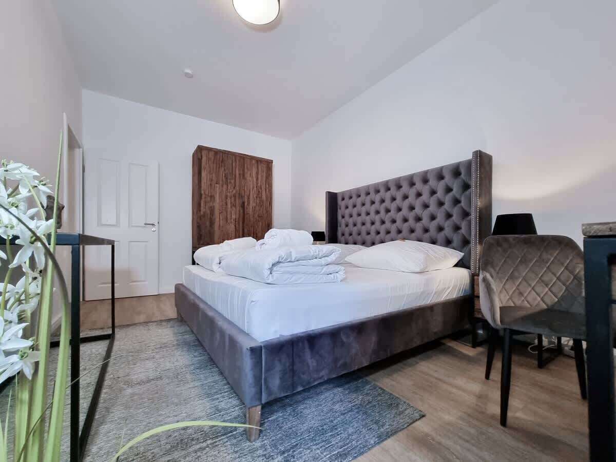 Een moderne slaapkamer met een groot bed, een houten garderobe, een bureau en een stoel.
