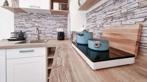 A modern kitchen with a stone backsplash, wooden shelves, and a built-in stove.