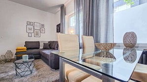 A modern living room with a glass dining table, a sofa, and a coffee table.