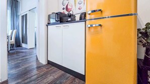 A modern kitchen with a yellow refrigerator, white cabinets, and a dining area with a table and chairs.