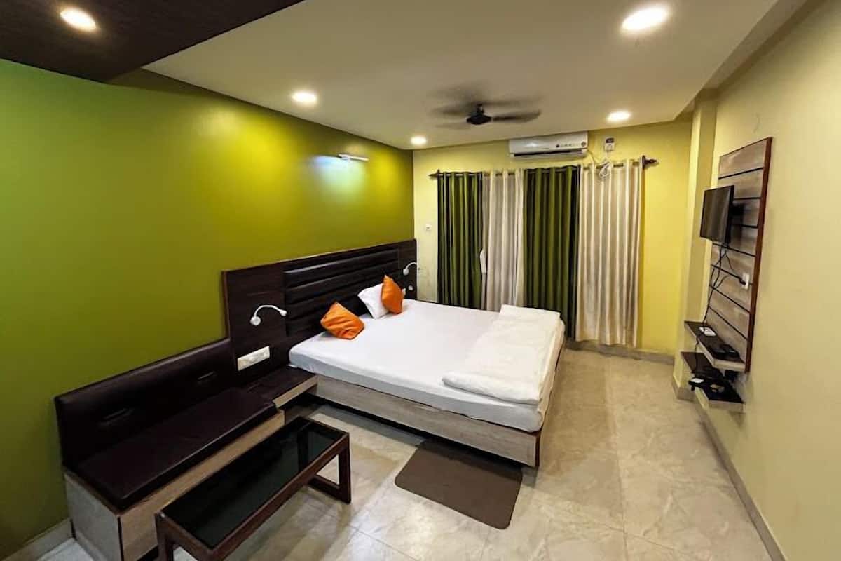 Habitación de hotel con cama, escritorio, silla, televisor y aire acondicionado.