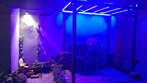 Ett svagt upplyst utomhusområde med en pergola av trä och krukväxter.