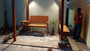 En träbänk under en pergola, med en krukväxt bredvid.