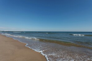 Een strand met helderblauw water en een zandstrand.