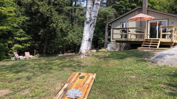 A wooden deck with a table and chairs, a tree, and a house with a deck and outdoor seating.