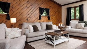 A cozy living room with two sofas, a coffee table, and a lamp. -  Private Adirondack Bear Retreat  (Athol)