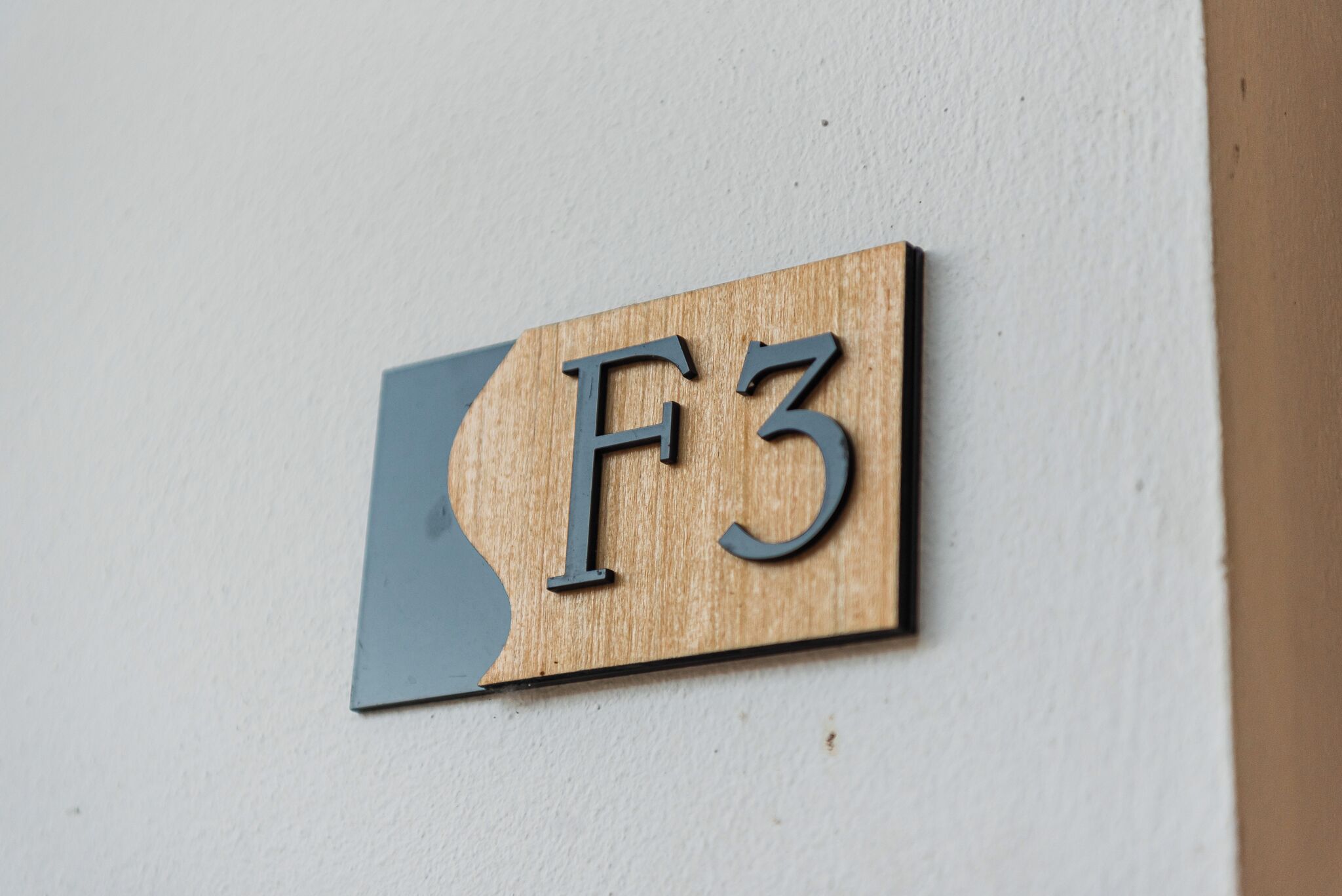 A wooden sign with the letters "F3" mounted on a wall.