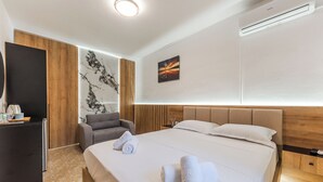 A hotel room with a large bed, a desk, a chair, and a wall-mounted air conditioner. - ApartHotel by PikHost (Shkodër)