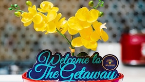 Eine rote Schüssel mit einem Schild, das 'Welcome to The Getaway' zeigt, und gelben Blumen.
