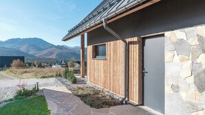 A modern house with a stone exterior, a wooden deck, and a stone pathway leading to the entrance. - Wierchy View - Loft Affair Collection (Koscielisko)