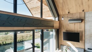 A modern living room with a large window, a dining area, and a TV mounted on the wall. - Wierchy View - Loft Affair Collection (Koscielisko)