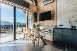 A modern kitchen with a large window, a flat-screen TV, and a dining area with chairs. - Wierchy View - Loft Affair Collection (Koscielisko)