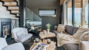 A modern living room with a fireplace, a staircase, a sofa, and a coffee table. - Wierchy View - Loft Affair Collection (Koscielisko)
