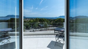 Een balkon met een helder uitzicht op een kustlandschap, inclusief een waterpartij en heuvels in de verte.
