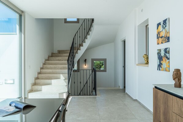 A modern interior with a staircase, a glass table, and artwork on the walls.