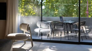 Una habitación moderna con un ventanal grande, un sofá y una zona de comedor con sillas y una mesa.