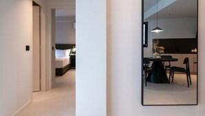Una habitación de hotel moderna con una cama, una mesita de noche y un área de comedor con una mesa y sillas.