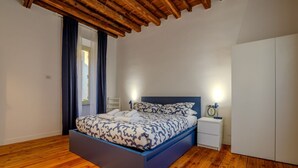 A bedroom with a bed, bedside tables, a wardrobe, and wooden flooring. - Cozy Flat Orso Navona square (Roma)