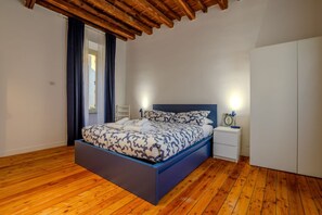 A bedroom with a bed, bedside tables, a wardrobe, and wooden flooring.
