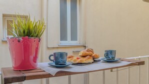 A balcony with a potted plant, two cups, and pastries on a tray. - Cozy Flat Orso Navona square (Roma)
