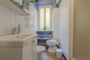 A bathroom with a sink, toilet, and window.