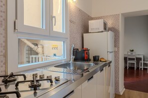 A modern kitchen with a gas stove, stainless steel sink, and a microwave. - Cozy Flat Orso Navona square (Roma)